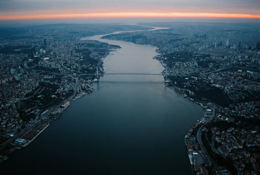 A broad strait at dawn dividing a city into two banks, one long bridge crossing it