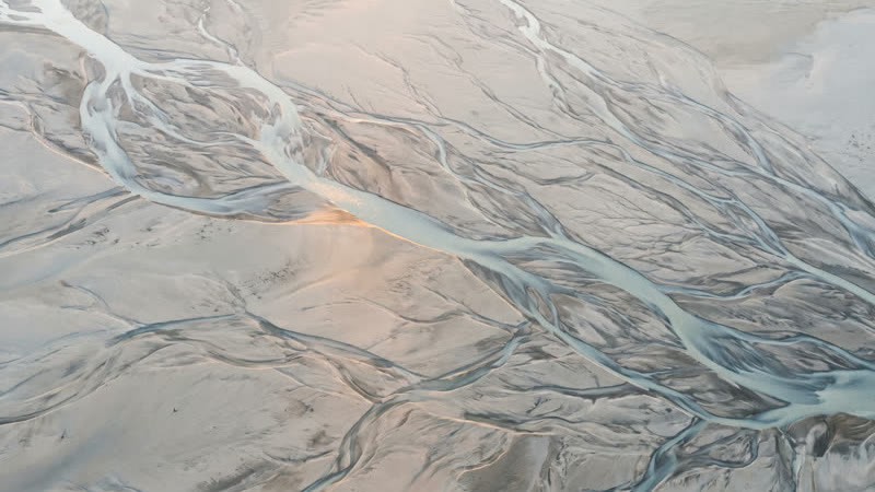 Pale, braided river channels spreading across a wide plain, seen from directly above.